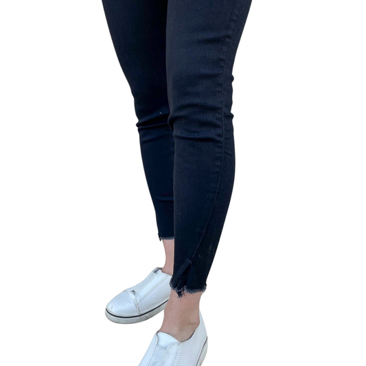 black high-rise skinny jeans with raw hem — close-up hem detail